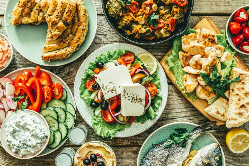 Selection of traditional greek food - salad, meze, pie, fish, tzatziki, dolma on wood background, top view